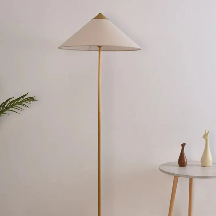 Lampadaire minimaliste rinessa avec pied en métal doré et abat-jour conique crème pour une décoration intérieure chaleureuse