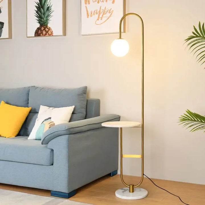 Lampadaire moderne gold-toned avec stand courbé, base en marbre blanc et éclairage raffiné syner