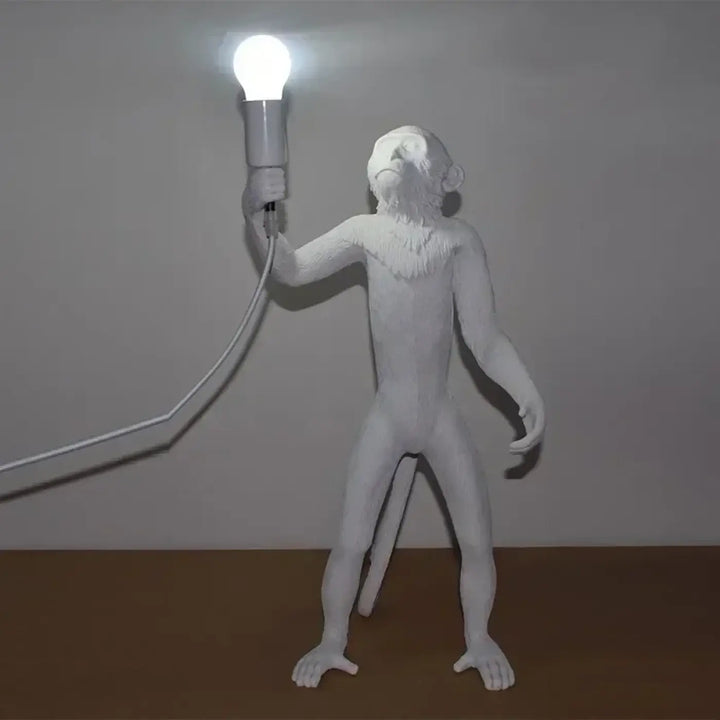 Lampadaire singe blanc avec détails fins et base élégante tenant une ampoule lumineuse dans sa main