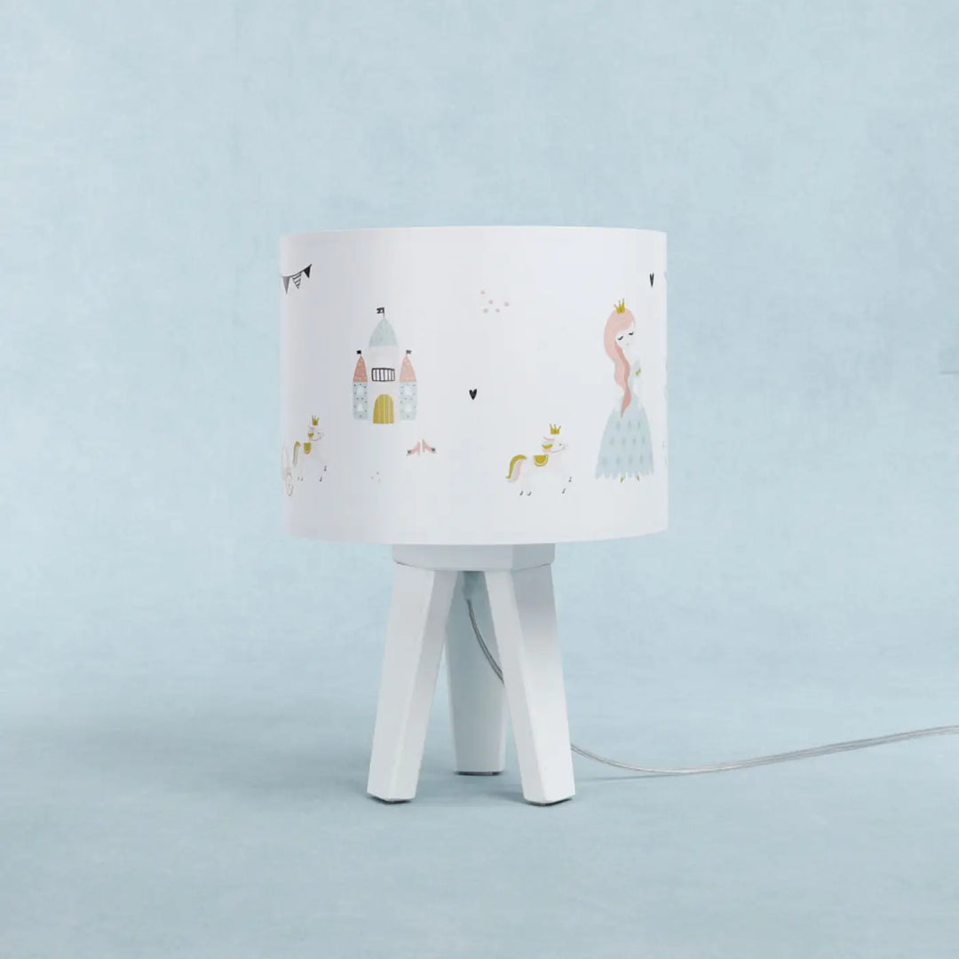 Lampe de table avec abat-jour blanc illustré de princesse féerique et château sur base trépied blanche minimaliste participe à créer une ambiance douce pour chevet blanche