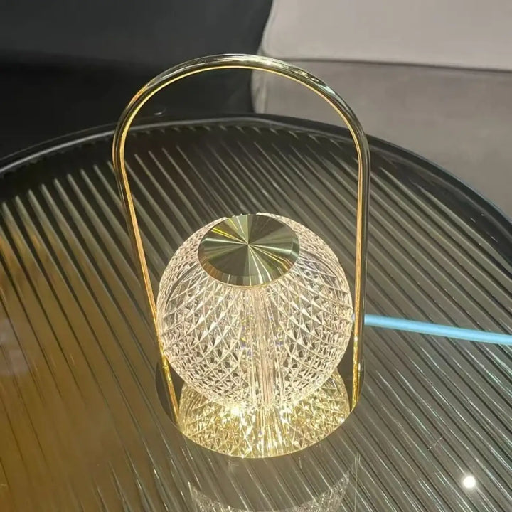 Lampe de chevet miu avec globe en cristal doré à design élégant apporte une présence lumineuse raffinée et un manche arquée