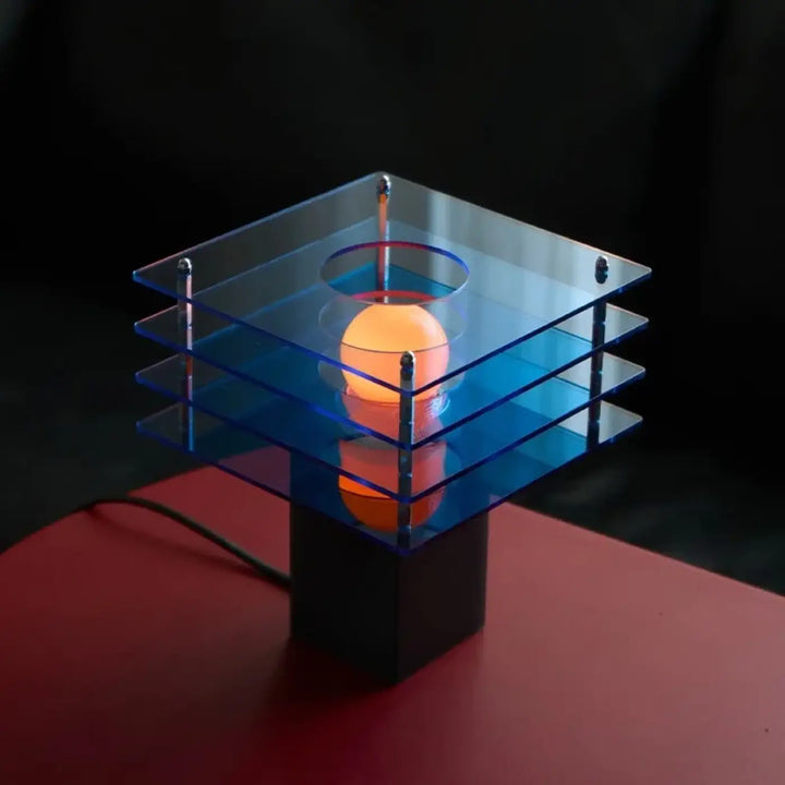 Lampe de chevet sunrise au design moderne avec base carrée en acrylique bleu translucide et orbe orange lumineux