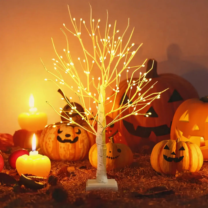 Lampe scintilla arbre lumineux décoratif blanc avec branches délicates et lumières jaunes entouré de citrouilles sculptées et bougies