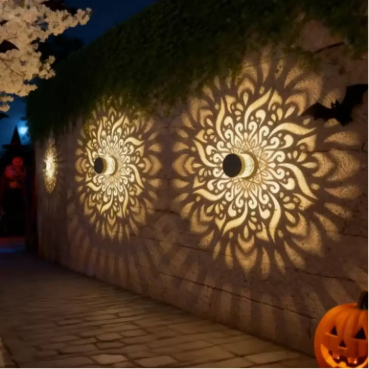 Luminaire extérieur qualih lampe murale orne en métal doré avec mandalas découpés et lumière chaude sur mur en pierre