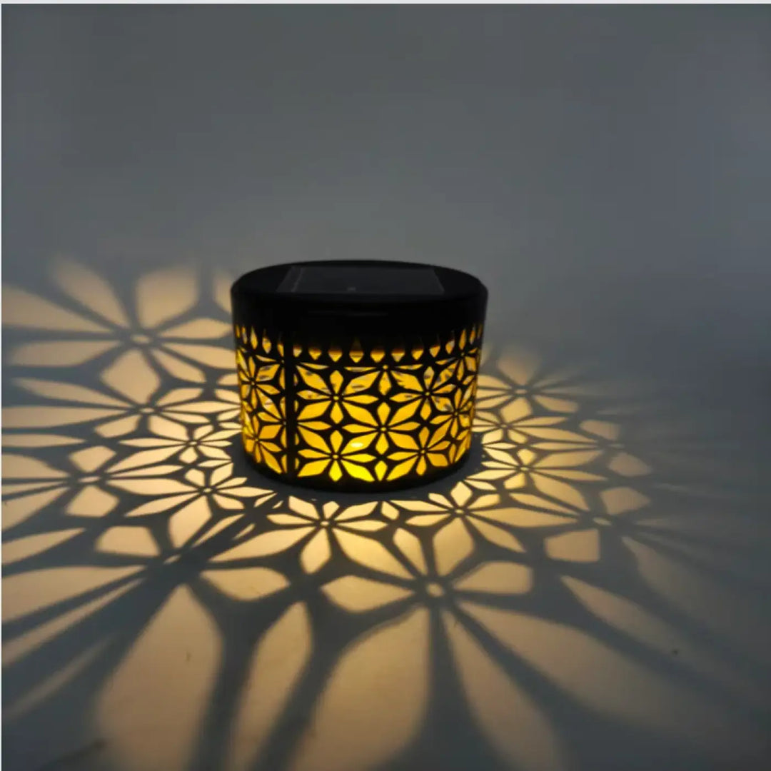 Lampe solaire extérieure noire avec motifs géométriques dorés projetant une ombre florale panneau solaire intégré charge complète rapide