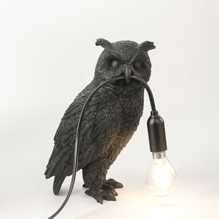 Lampe de table owly noire en forme de hibou avec surface texturée plumes et ampoule visible pour décoration intérieure au caractère affirmé