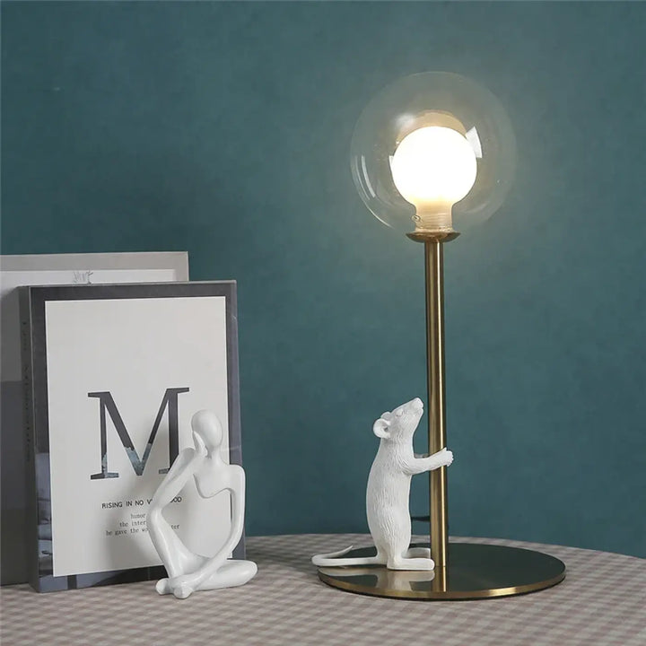 Lampe de table valavo en résine blanche avec souris tenant un poteau en fer type laiton et globe en verre clair