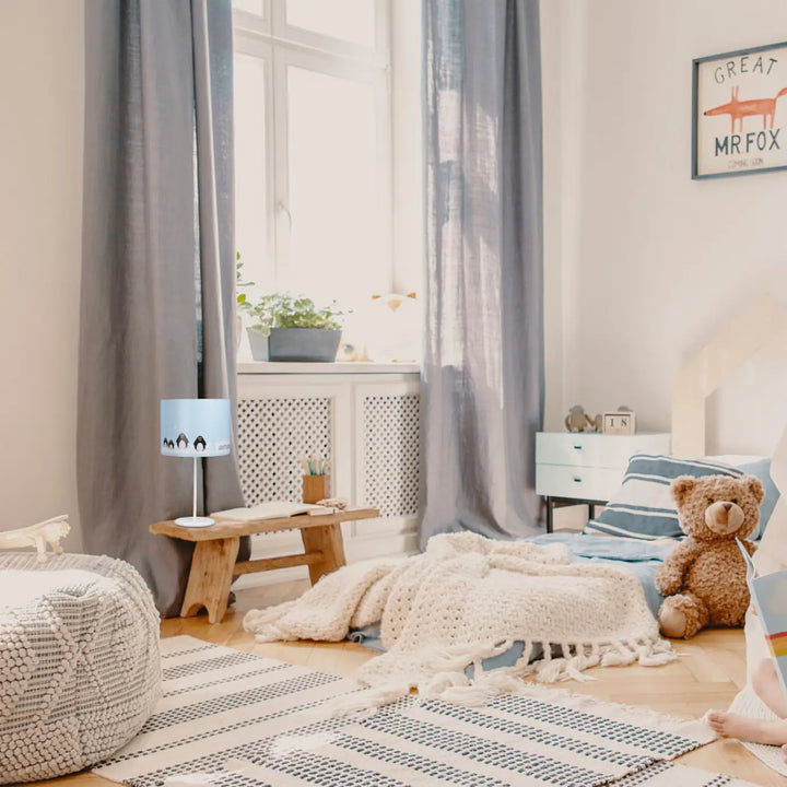 Lampe de table bleu clair avec design aux adorables manchots posée sur un banc en bois dans la collection sweet dreams