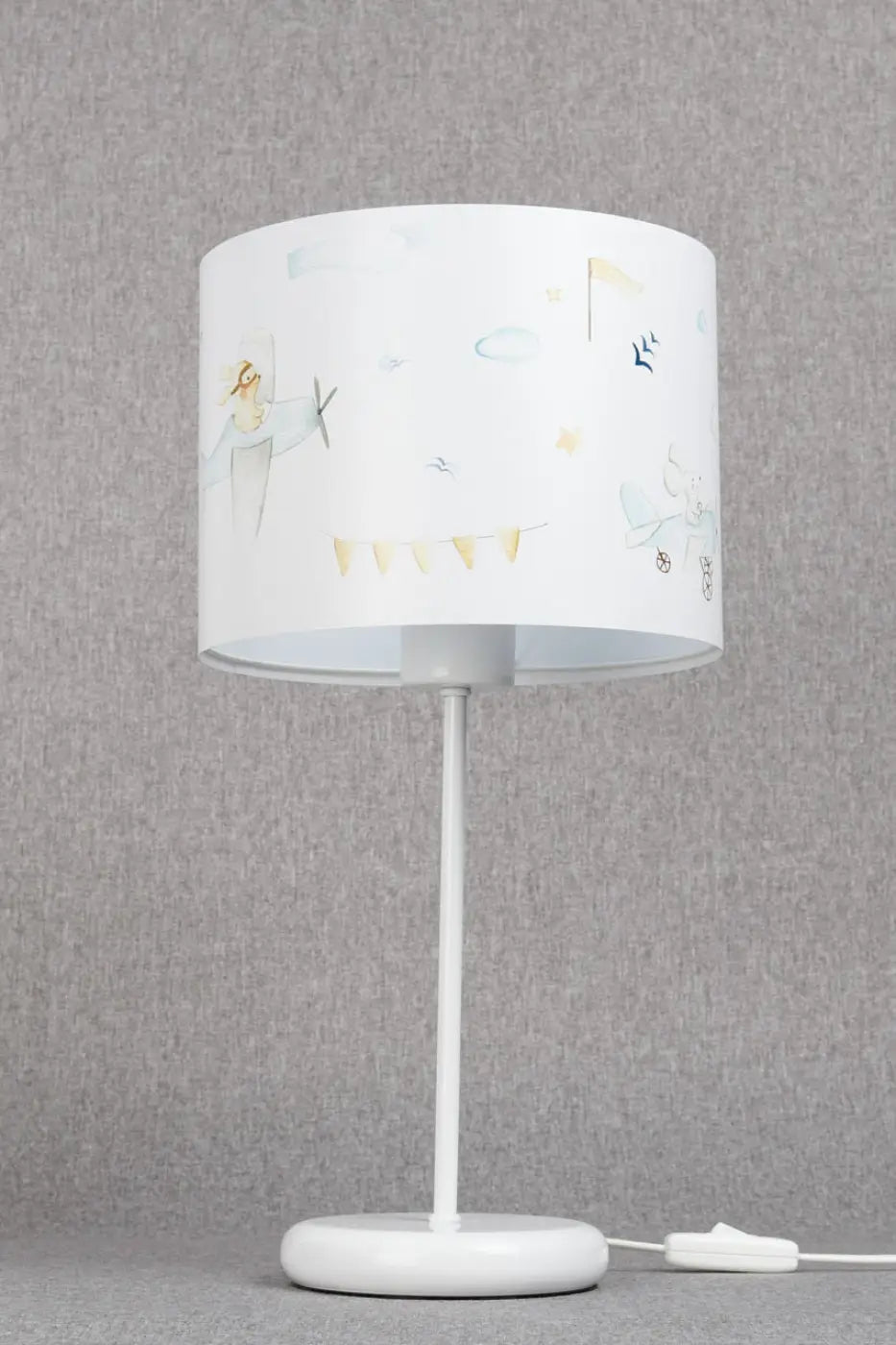 Lampe de table blanche avec abat-jour cylindrique illustré d’avions, nuages rêvés et décor avions en bleu clair et blanc