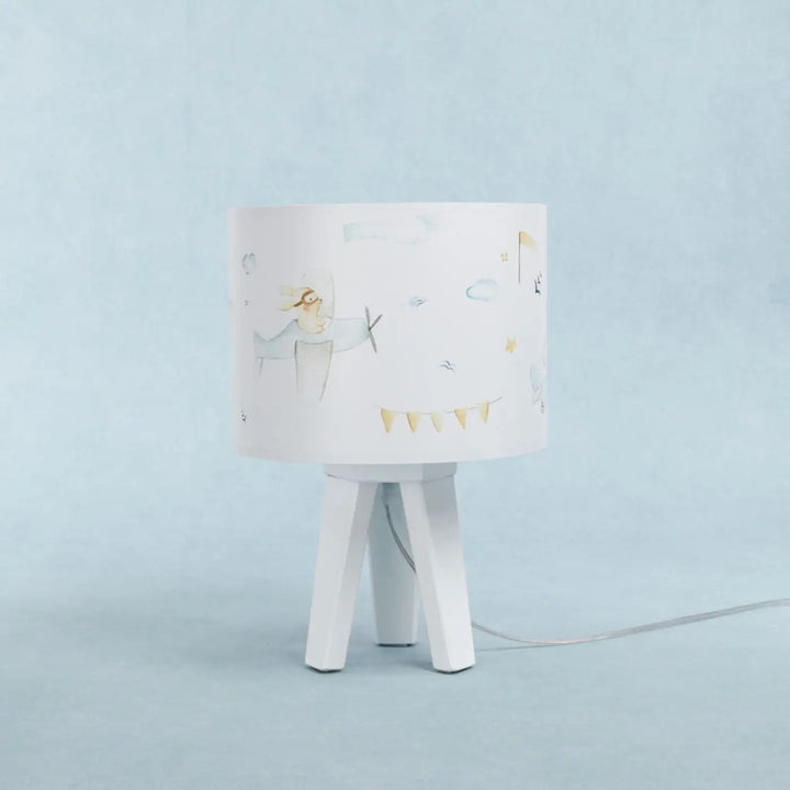 Lampe de table blanche avec abat-jour cylindrique illustré d avions et bannière sur base tripode bleu enfant pour un charmant univers féerique