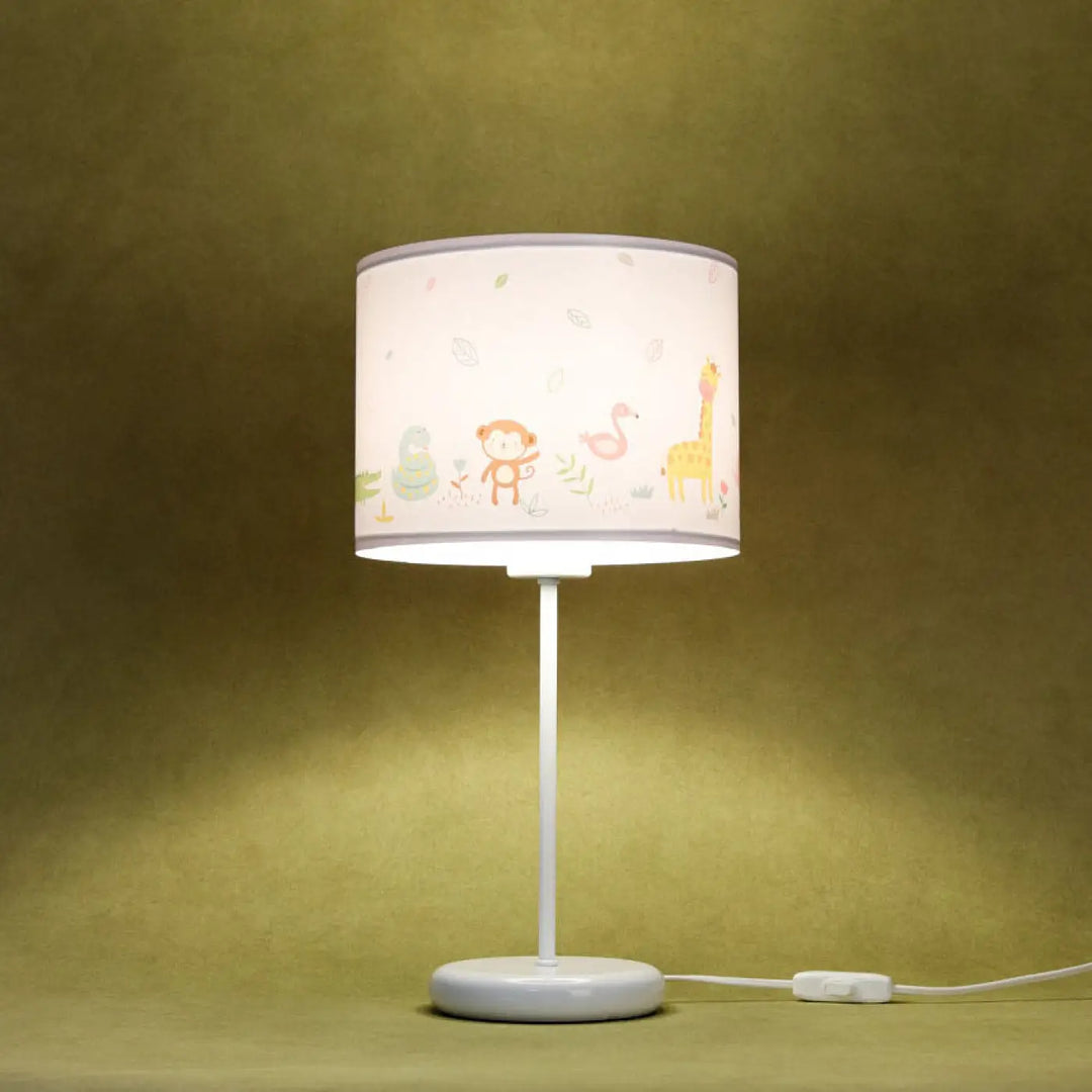 Lampe de table vert clair avec abat-jour cylindrique blanc motif savane coloré sur table blanche