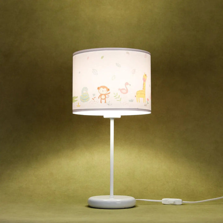 Lampe de table vert clair avec abat-jour cylindrique blanc motif savane coloré sur table blanche