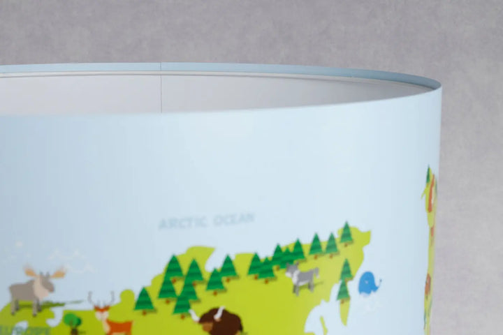 Lampe de table avec abat-jour cylindrique bleu clair et vert aux animaux illustrés sur fond blanc