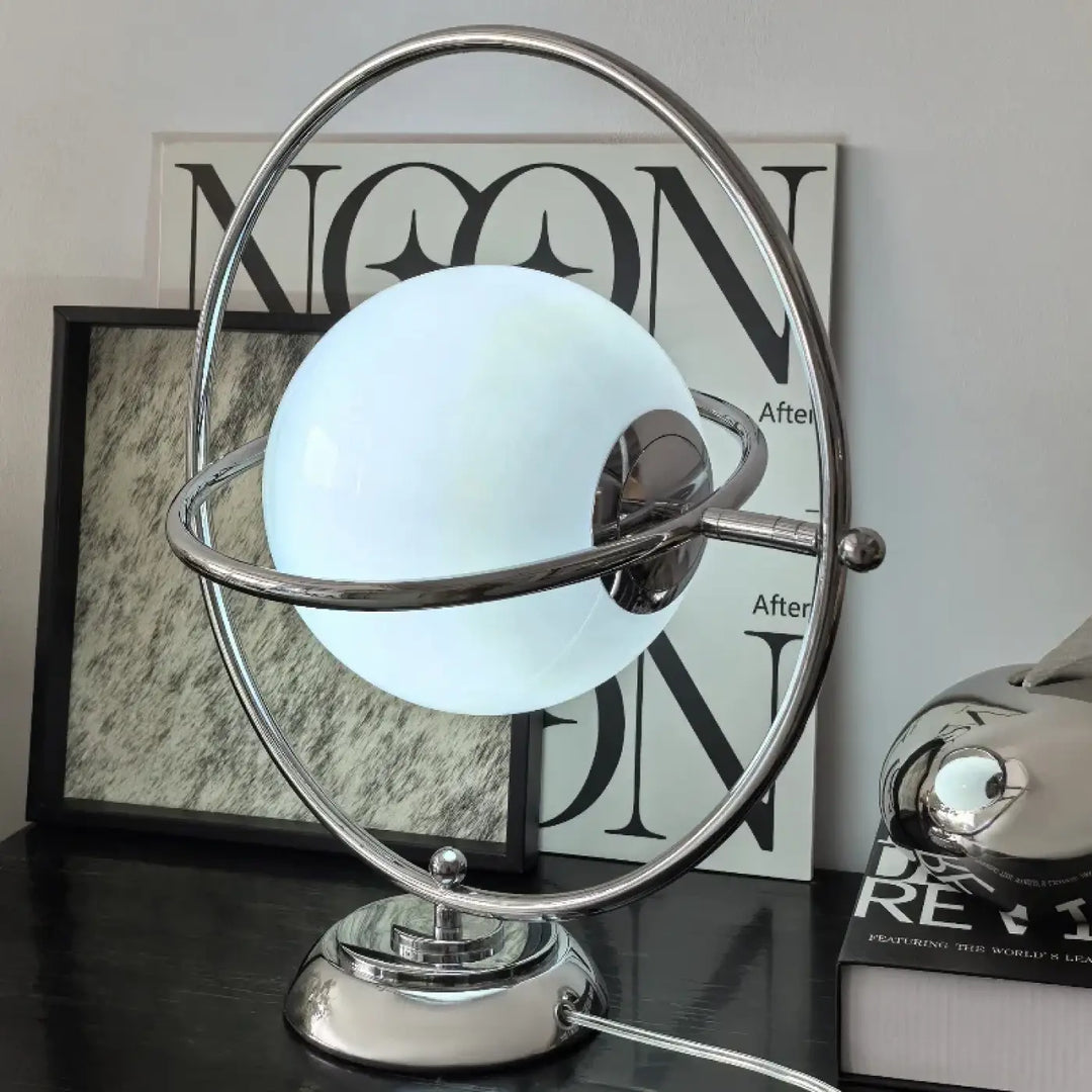 Lampe de table dessi avec globe blanc lumineux effet planète encadré de anneaux chromés sur base métallique élégante