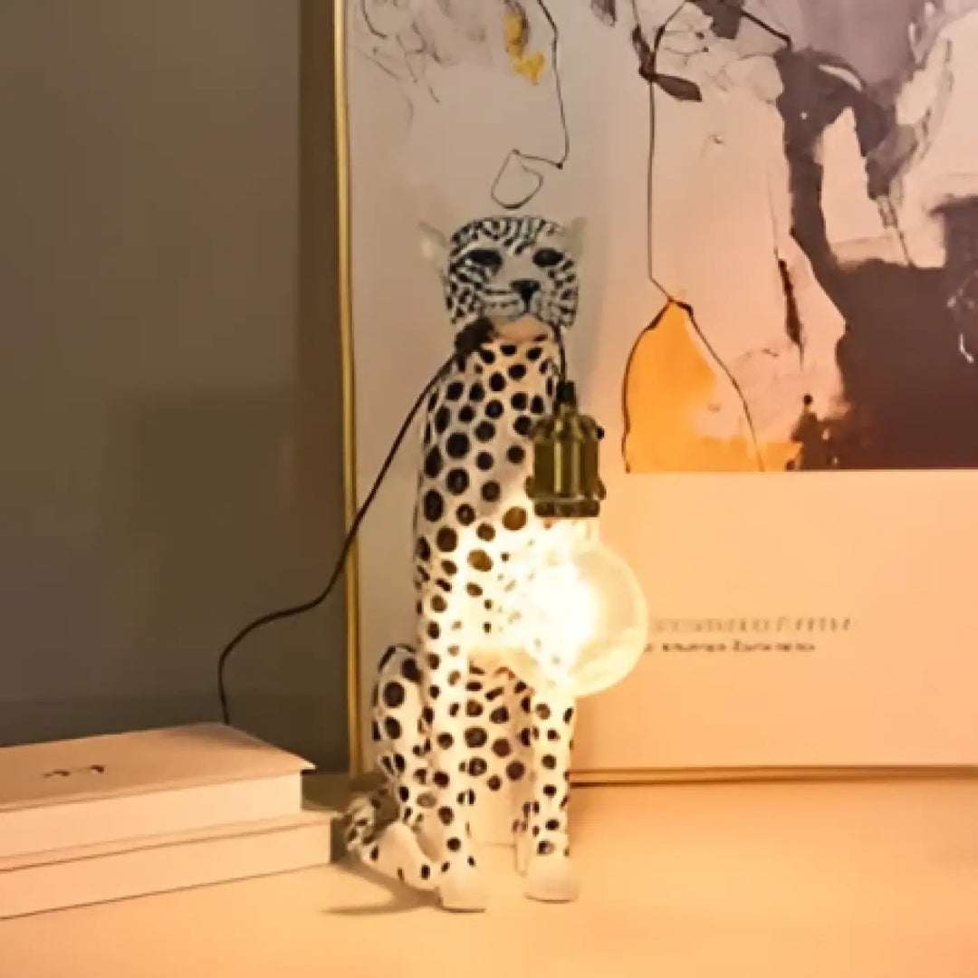 Lampe de table felina en céramique blanche en forme de chat tacheté avec ampoule suspendue visible pour table design léopard