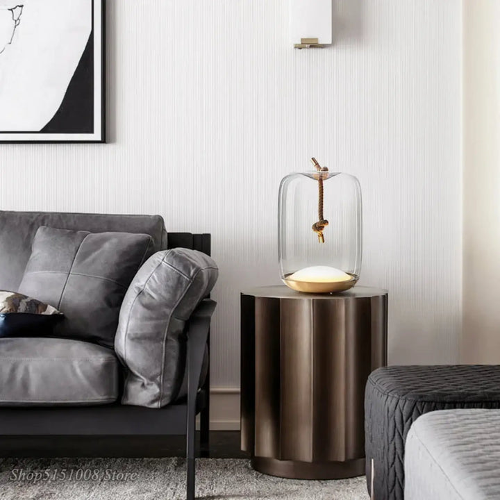 Lampe de table aeris en verre avec base dorée et corde suspendue pour une lumière douce en décoration intérieure moderne