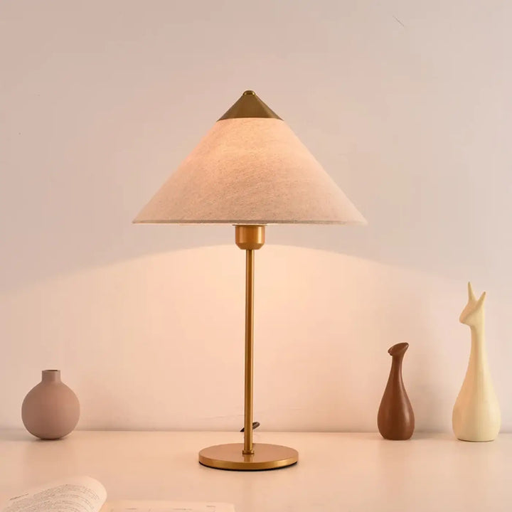 Lampe de table rine en laiton avec abat-jour conique en tissu beige pour une table moderne et une ambiance chic