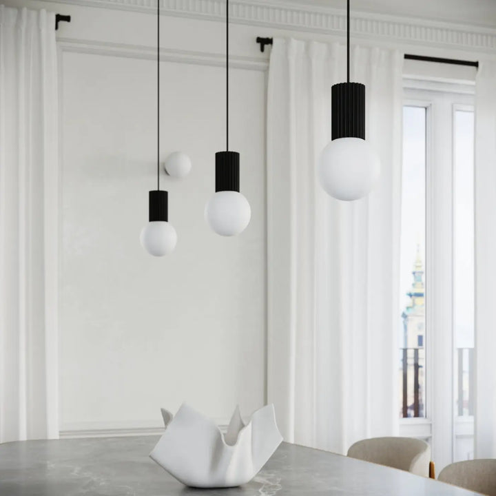 Lampe a poser halo noir avec trois suspensions minimalistes en verre laiteux et abat-jour cylindrique noir ribbé répond aux besoins design