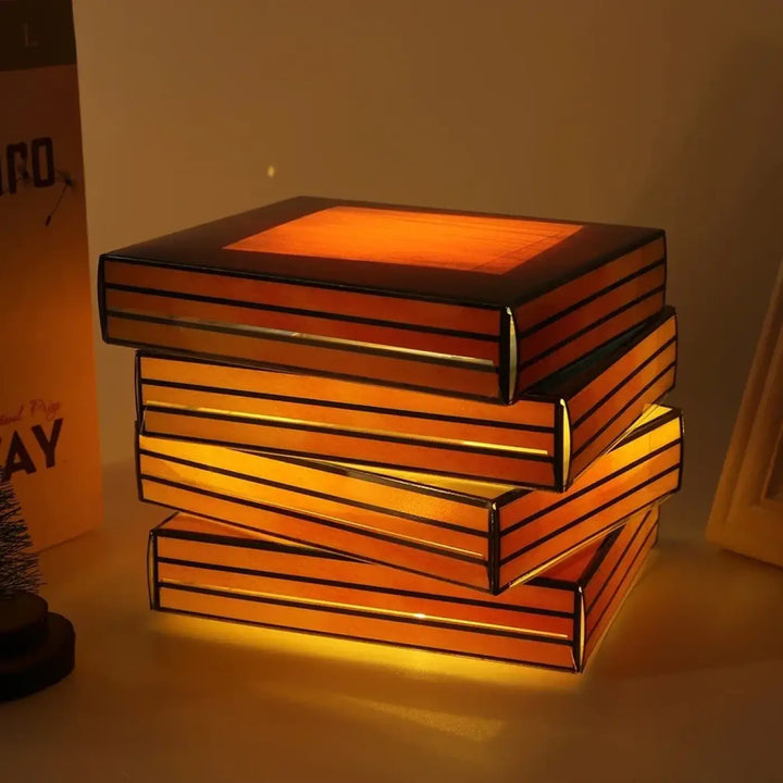 Lampe de table originale lecturia en forme de livres aux couleurs avec un éclat orange chaud et bordure noire pour décoration intérieure