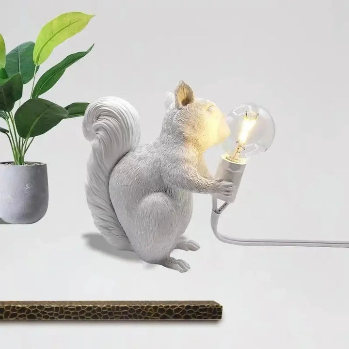 Lampe de table écureuil en résine blanche avec finition texturée tenant une ampoule edison illuminée design écureuil