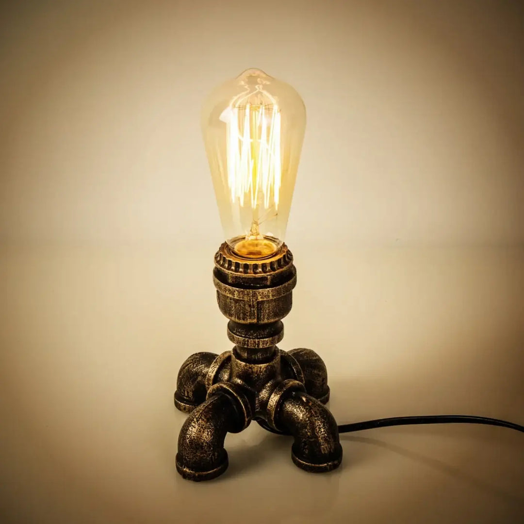 Lampe de table forge style industriel avec base en tuyau finition laiton et ampoule edison pour une décoration intérieure chaleureuse