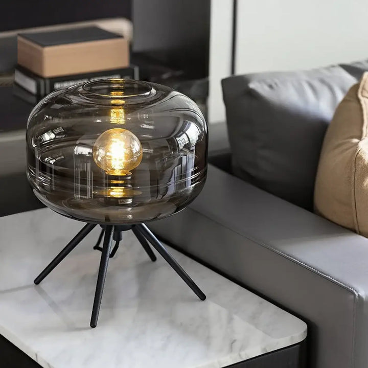 Lampe de table grisa en verre fumé avec base trépied design minimaliste et ampoule dorée exposée cadeau original
