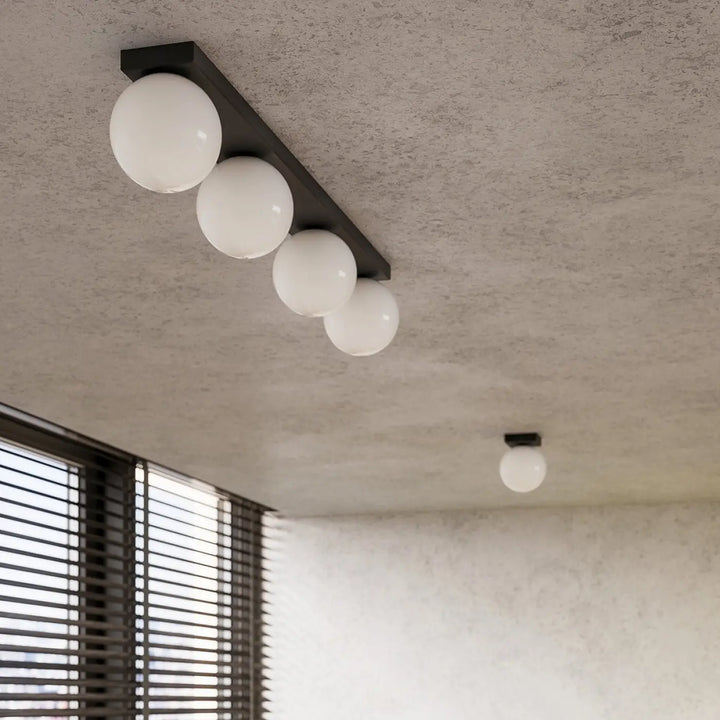 Luminaire plafonnier yoli 2 noir avec quatre globes en verre blanc pour un plafon yoli classe à part