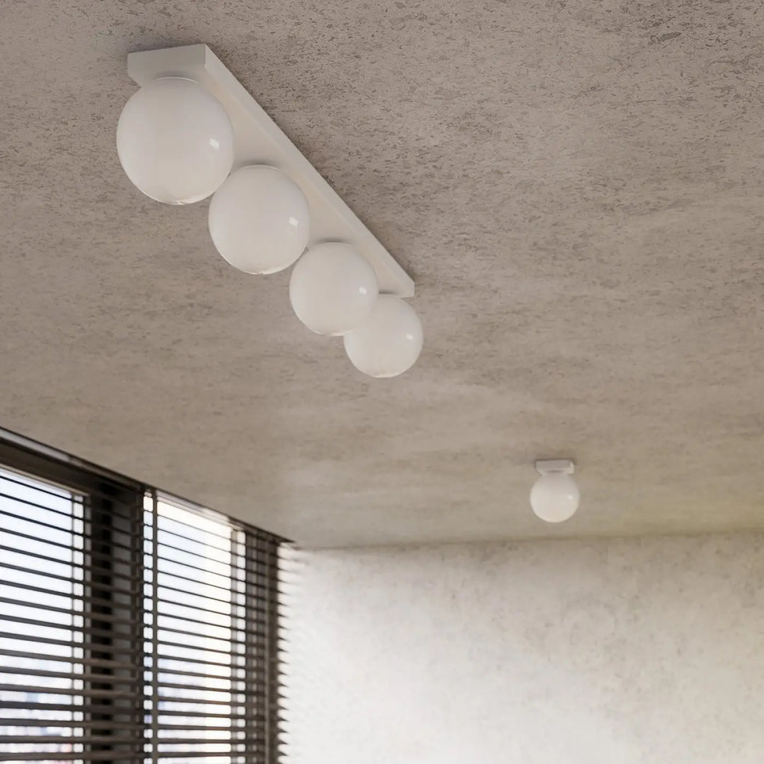 Luminaire plafonnier plafon yoli blanc avec globe sphérique et quatre ampoules sur barre rectangulaire minimaliste classe à part