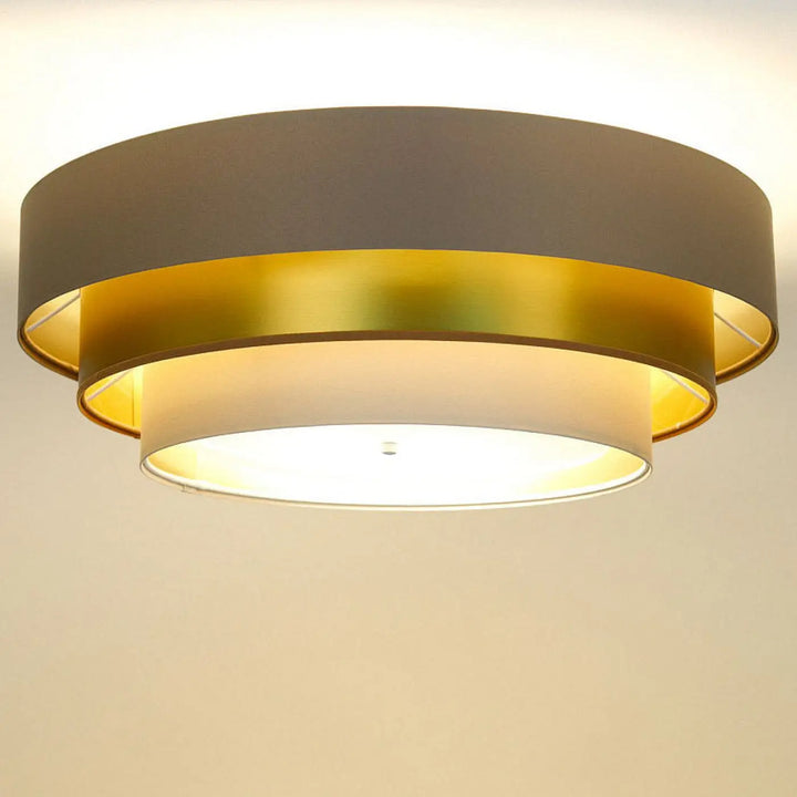 Luminaire plafonnier triniti elegant beige avec design en anneaux métalliques dorés et gris mat émettant une lumière chaude