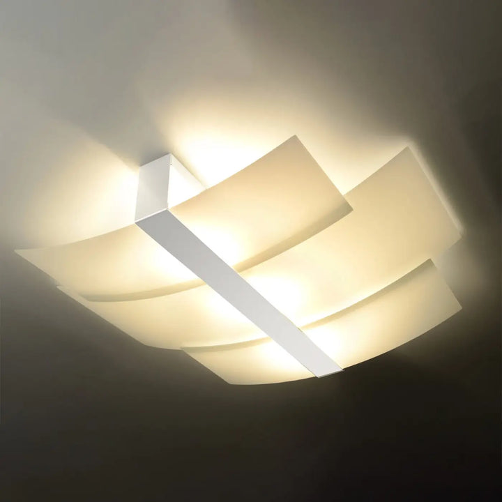 Luminaire plafonnier celia blanc avec panneaux géométriques superposés émettant une lumière chaude design intemporel