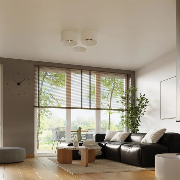 Canapé sectionnel en cuir noir avec coussins blancs présenté avec plafonnier telesto blanc au design minimaliste