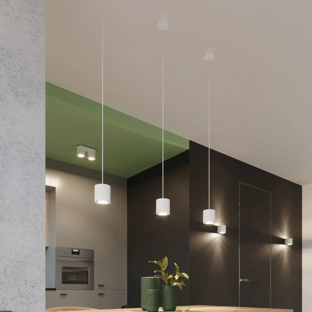 Trois plafonniers orbis cylindriques blancs suspendus par des fils fins avec finition en bois naturel