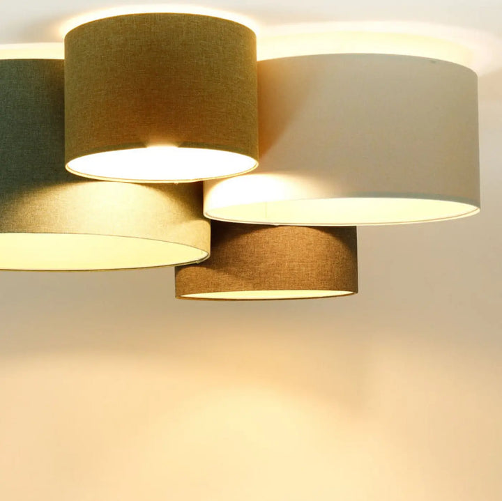 Luminaire plafond avec quatre abat-jours cylindriques en tissu naturel vert gris beige et marron dans un style boho élégant