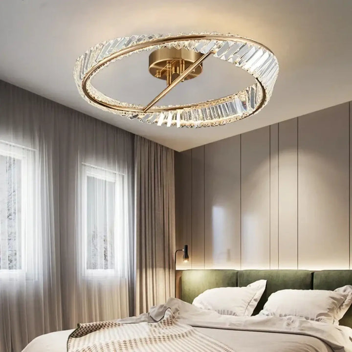 Plafonnier circulaire à finition dorée, avec des anneaux en cristal facetté et un luminaire central en laiton.