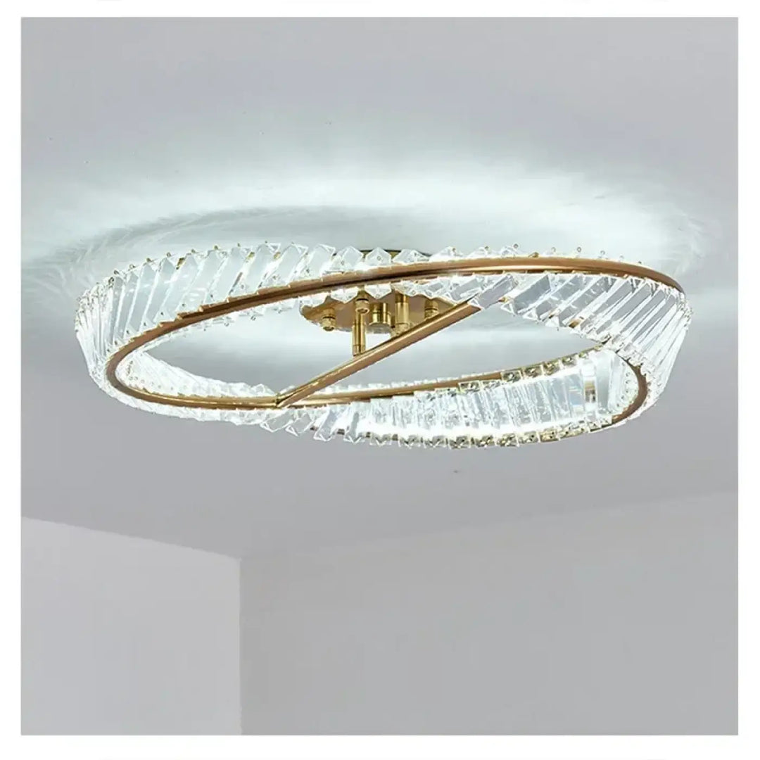 Un plafonnier double anneau moderne avec des montures en métal à teinte dorée et des éléments en cristal transparent, facettés.
