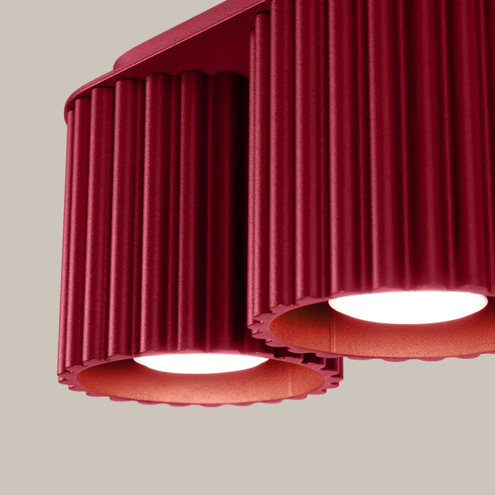 Luminaire plafonnier aura 2 bordeaux en métal rouge cannelé avec deux luminaires circulaires allumés et forme unique inspirée