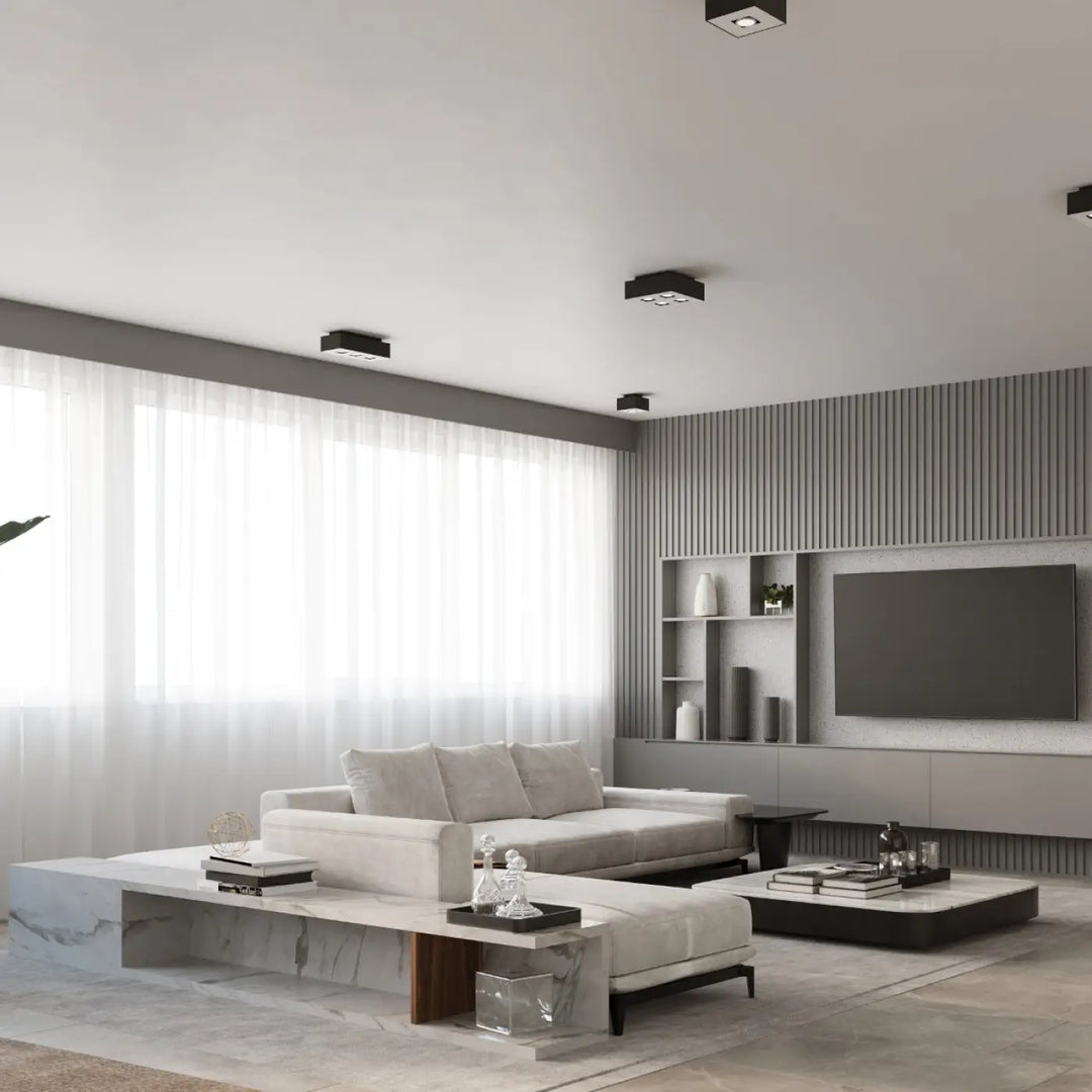 Plafonnier moderne mono noir avec sources lumineuses et spot allongé dans salon minimaliste avec canapé blanc et tables en marbre