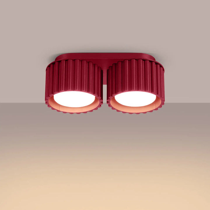 Luminaire plafonnier aura 2 bordeaux avec forme unique inspirée de doubles abat-jours cylindriques en verre cannelé rouge sur base métallique élégante