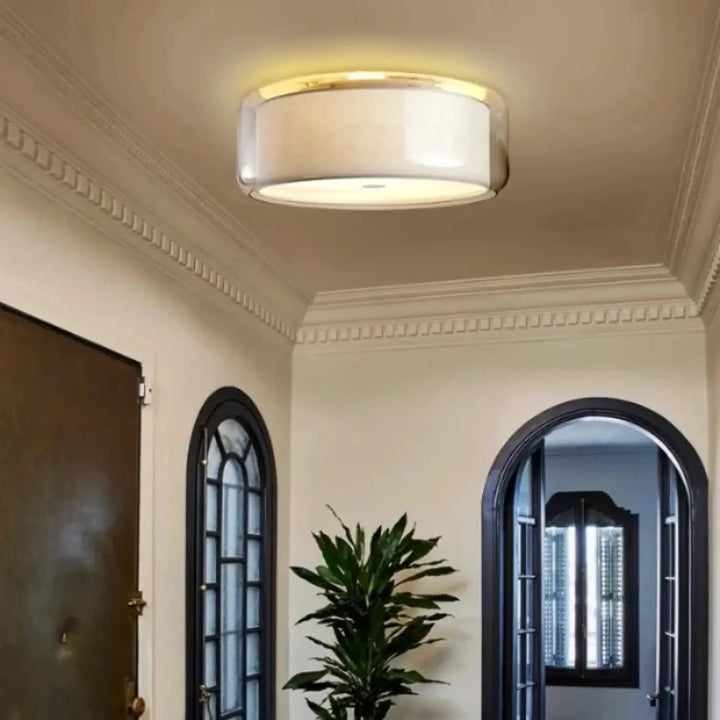 Luminaire plafonnier oreane avec abat-jour cylindrique en verre dépoli et contour métallique doré contribue à créer une ambiance moderne