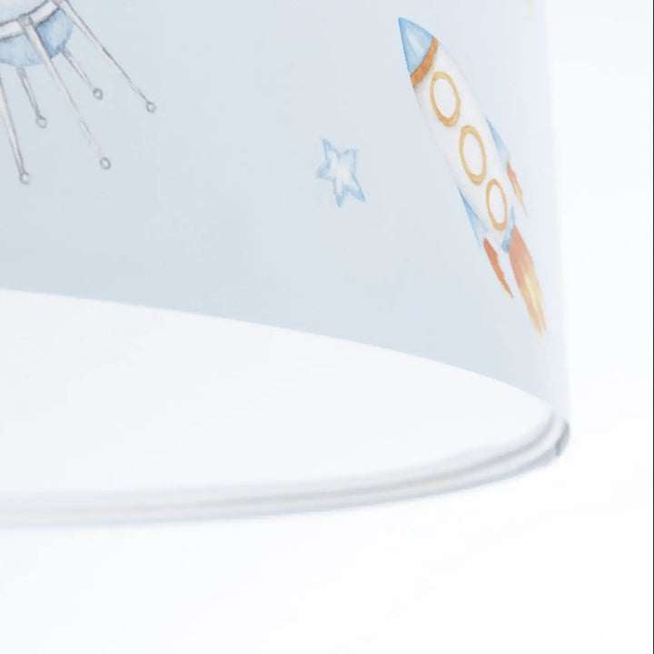 Luminaire plafonnier enfant bleu avec abat-jour clair décoré d’une fusée orange blanche et motif espace étoiles