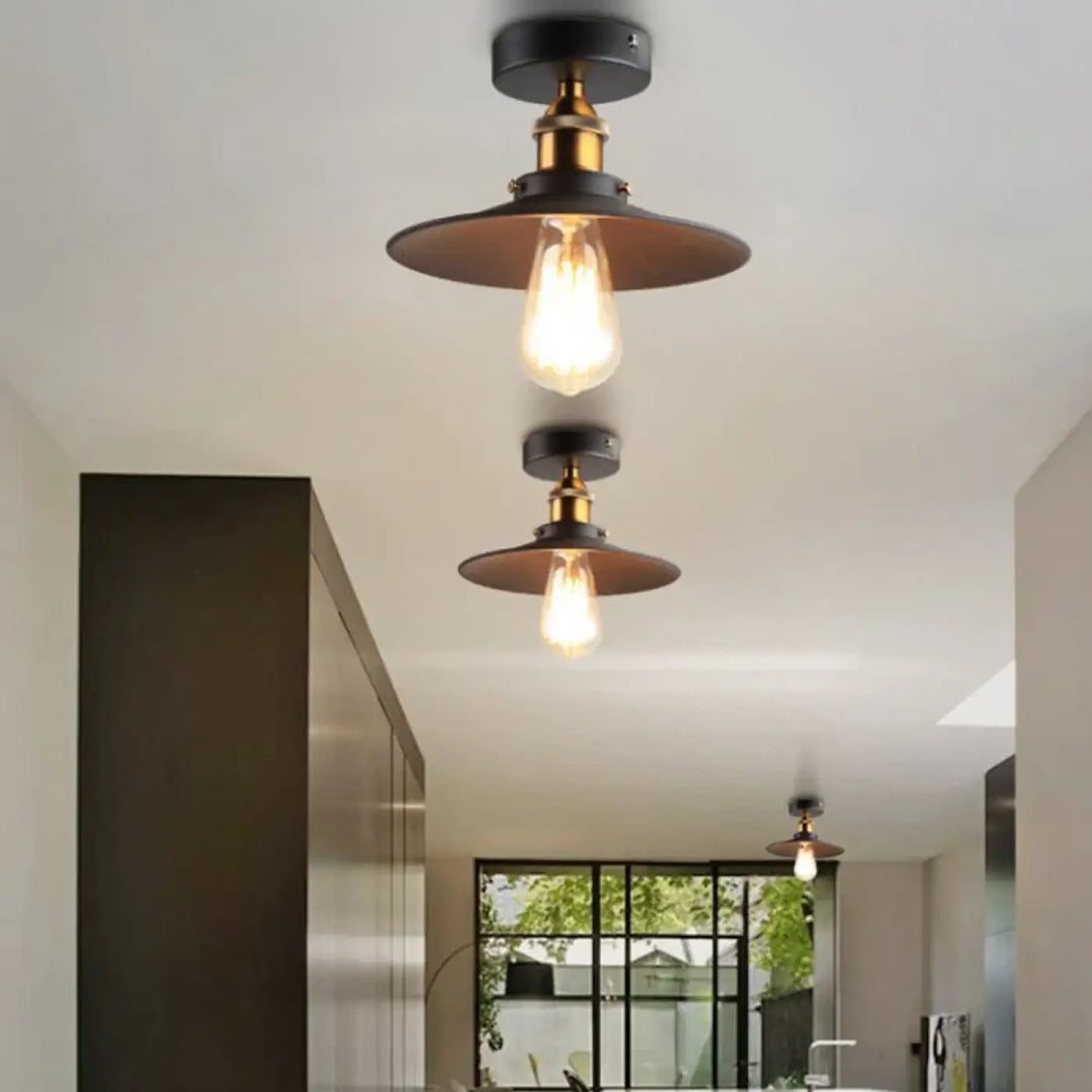 Luminaire plafonnier style industriel avec abat-jour noir mat, accents en laiton et ampoule edison apparente pour décoration intérieure