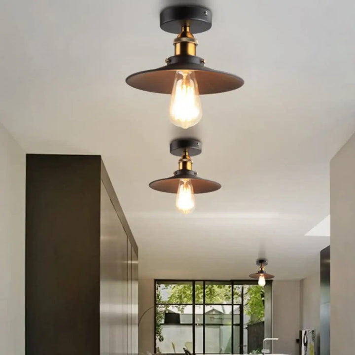 Luminaire plafonnier style industriel avec abat-jour noir mat, accents en laiton et ampoule edison apparente pour décoration intérieure