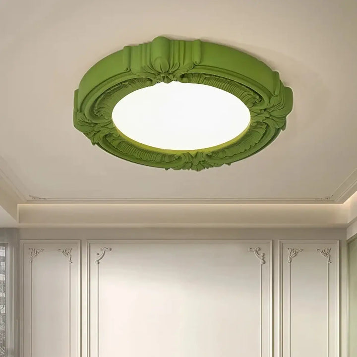 Luminaire plafonnier artistique rosalia vert avec moulures florales et ruban autour d un centre illuminé circulaire
