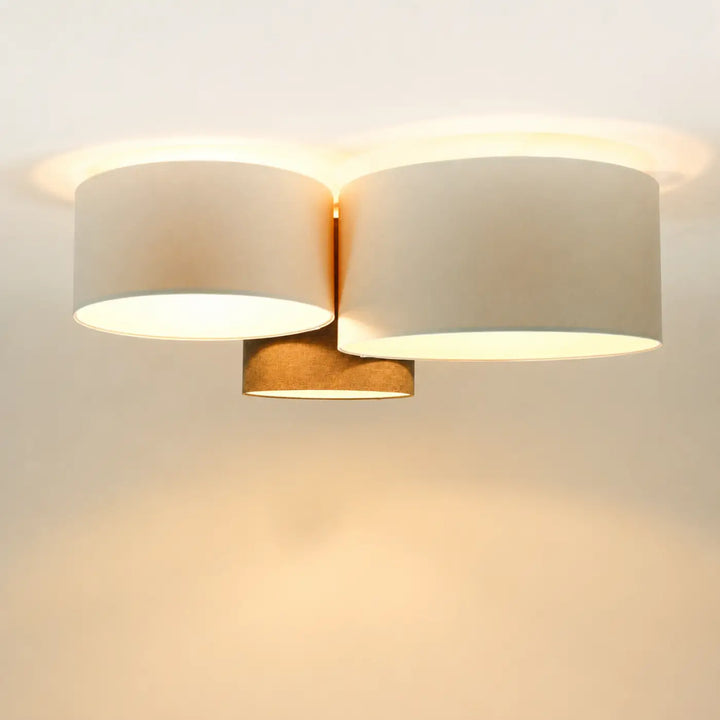 Luminaire plafond moderne avec deux abat-jours cylindriques en tissu beige et base centrale en métal couleur laiton naturel