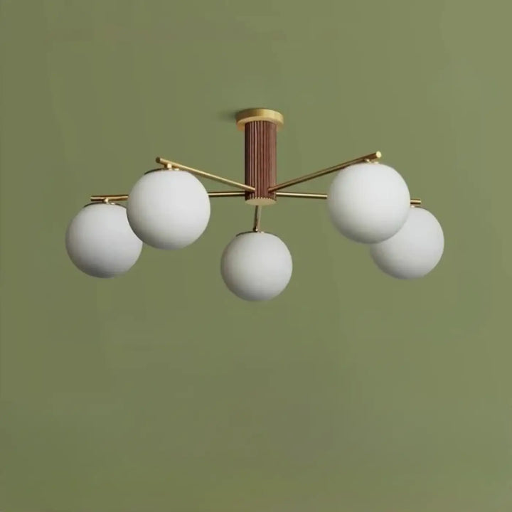 Luminaire plafonnier moderne cortix avec cinq globes en verre blanc suspendus à une structure en laiton cuivre finition noyer
