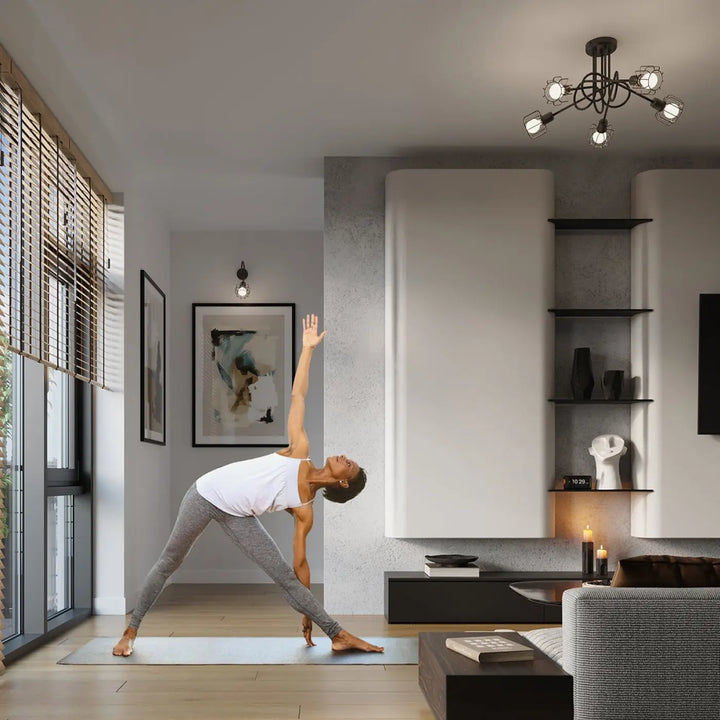 Une femme en débardeur blanc et legging gris réalise une pose de yoga sur un tapis bleu clair près d un luminaire plafonnier beluci 2 noir style loft collection beluci appliques murales