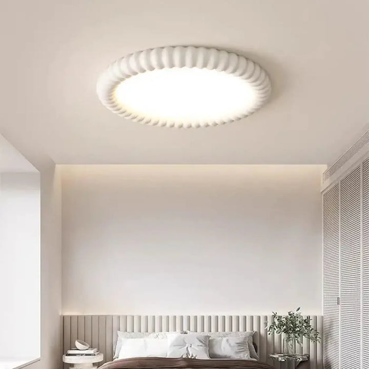 Lampe de plafond circulaire blanche avec un bord extérieur texturé et nervuré et un diffuseur central lisse.
