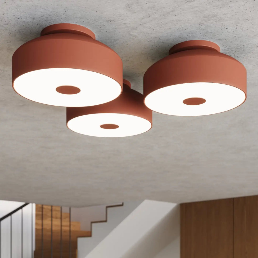 Plafonnier omiq rouge ocre en terre cuite moderne avec trois têtes lumineuses circulaires allie simplicité et design exceptionnel