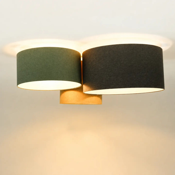 Luminaire plafonnier moderne avec deux abat-jours cylindriques en tissu vert gris et noir sur base en laiton chaud naturel