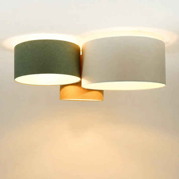 Luminaire plafonnier moderne avec deux abat-jours cylindriques en tissu crème et gris vert monté sur base en laiton naturel